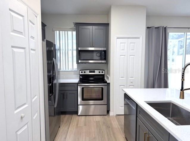 A kitchen features dark gray cabinets, stainless steel appliances, and a white countertop island — 1282 S BEACH CIRCLE, KISSIMMEE, FL