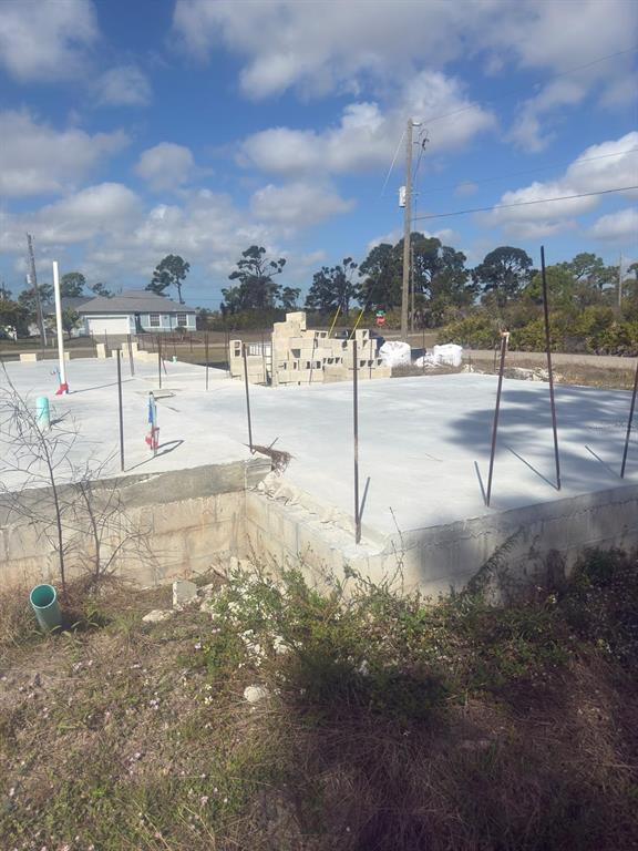 A concrete foundation slab with vertical rebar and stacked blocks sits on a construction site — 3 TAFFRAIL LANE, PLACIDA, FL