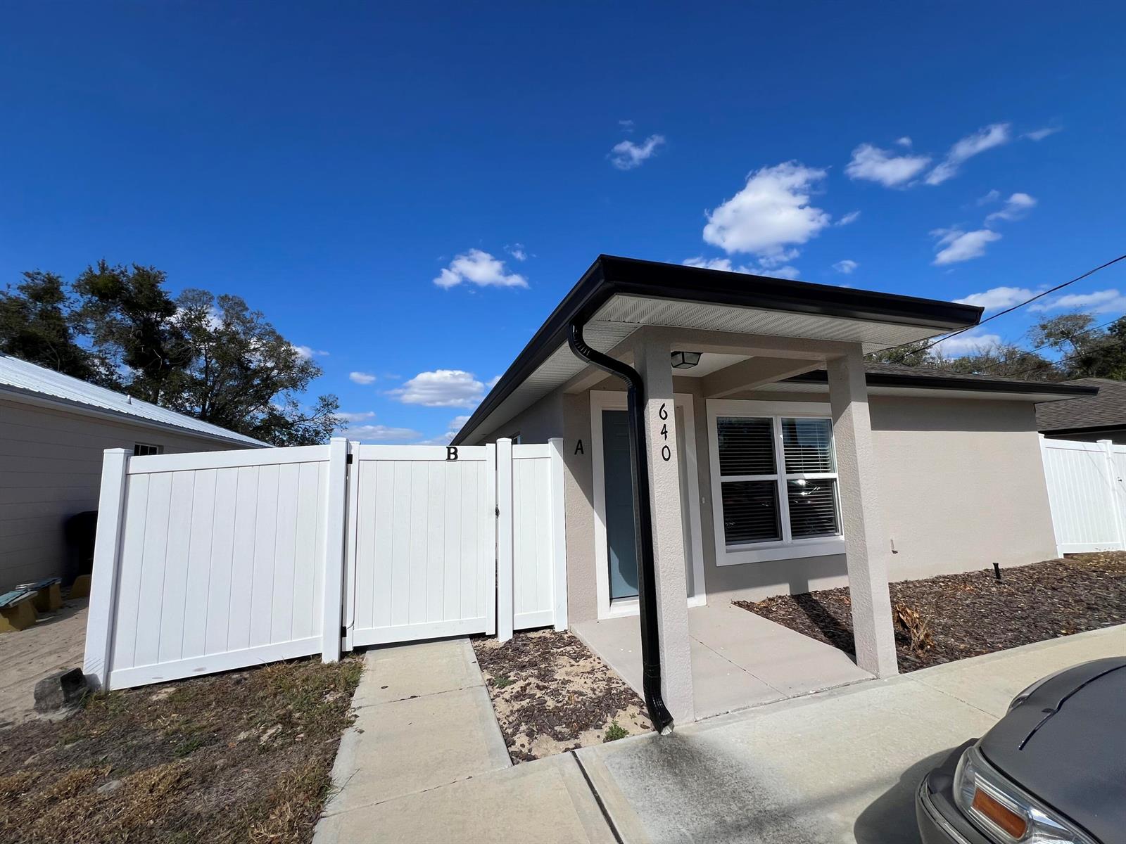 A single-story house exterior features a white vinyl fence, a covered porch, and address numbers — 640 E Grapefruit Avenue, FL 33850, FL