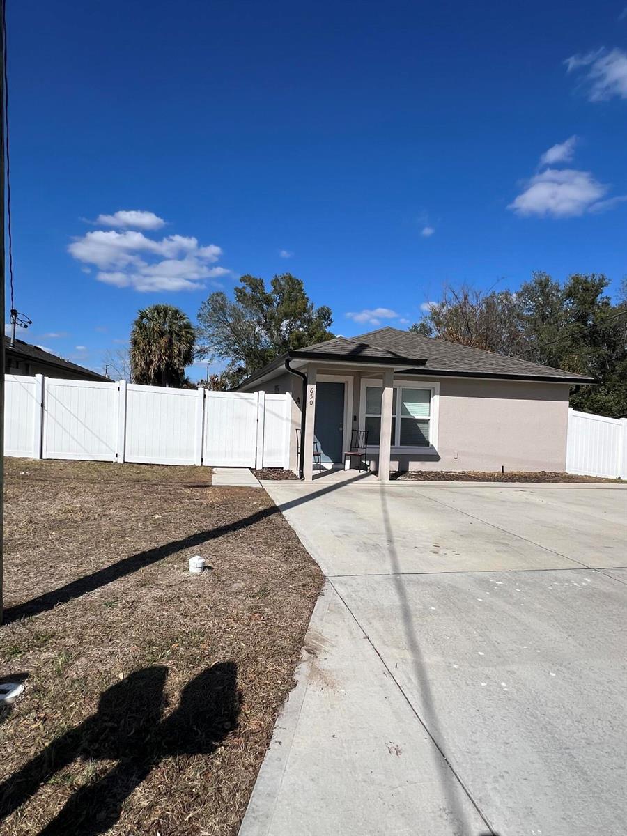 A single-story house with a concrete driveway and a white vinyl fence under a blue sky — 640 E Grapefruit Avenue, FL 33850, FL