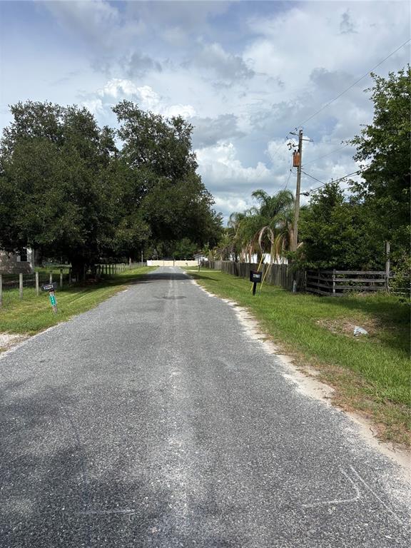A paved road stretches between grassy shoulders lined with trees, fences, and utility poles — 4670 ANDERSON ROAD, KISSIMMEE, FL