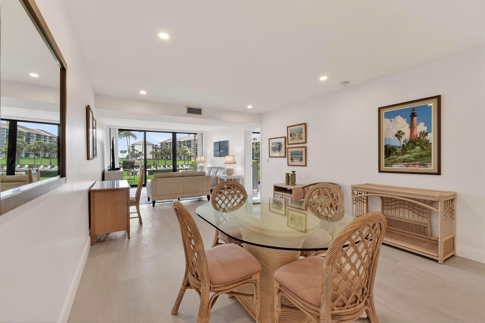 A dining area with a glass-topped table and wicker chairs opens to a living room — 301 S Seas Drive # 104, Jupiter FL 33477, JUPITER, FL