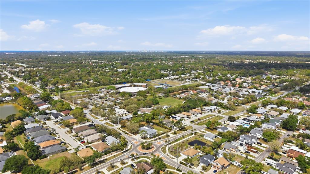 An aerial view shows a suburban neighborhood with houses, streets, a roundabout, and green spaces — 5251 ASHTON ROAD, SARASOTA, FL