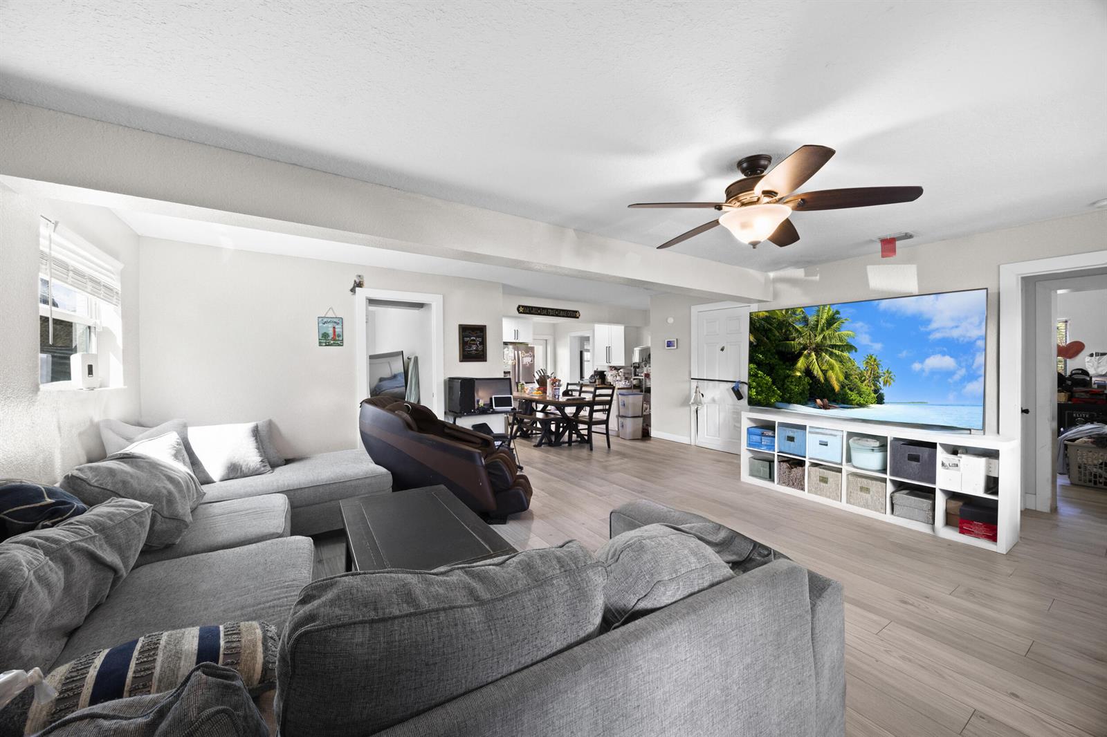 A living room features a grey sectional sofa, a large television, and light wood flooring — 2517 SE Normand Street, Stuart FL 34997, STUART, FL