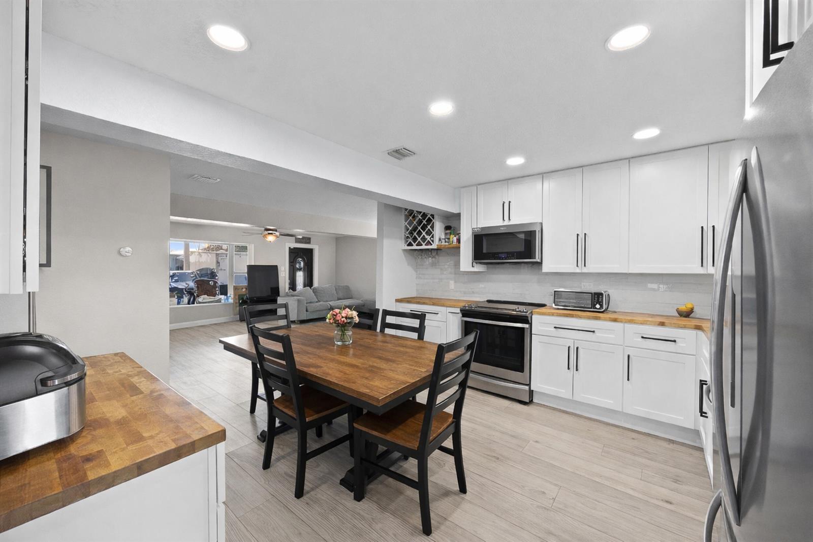 A kitchen with white cabinets, butcher block countertops, and a dining table in the center — 2517 SE Normand Street, Stuart FL 34997, STUART, FL