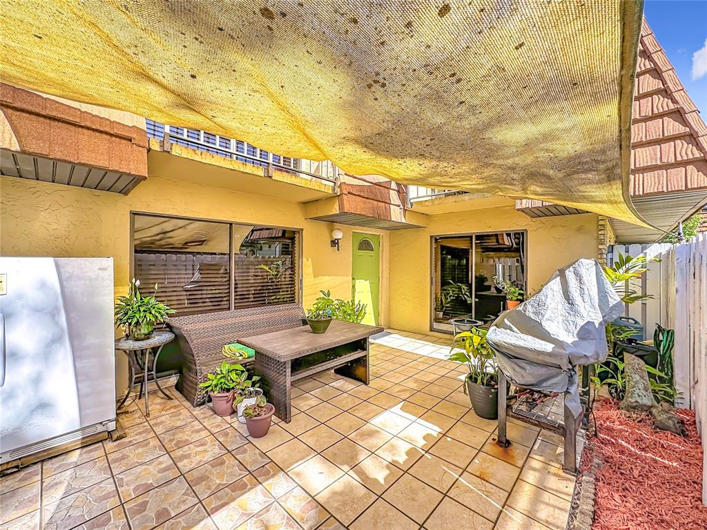 A paved patio features a table, seating, a covered grill, and a yellow shade canopy — 1458 N LAWNWOOD CIRCLE UNIT 24A, FORT PIERCE, FL