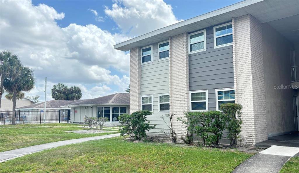 A two-story apartment building with light-colored brick accents and gray horizontal siding — 860 SKY LAKE CIRCLE UNIT C412, ORLANDO, FL