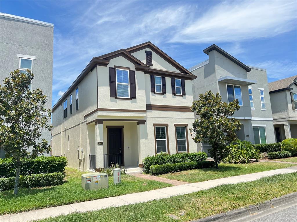 A two-story house with beige stucco siding, brown trim, and a small front porch — 7867 BERKSHIRE OAK ALLEY, WINDERMERE, FL