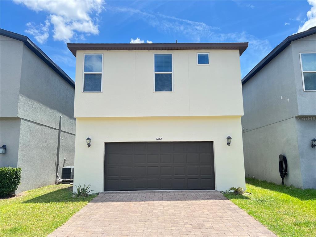 The exterior of a two-story house features a large dark brown garage door and driveway — 7867 BERKSHIRE OAK ALLEY, WINDERMERE, FL