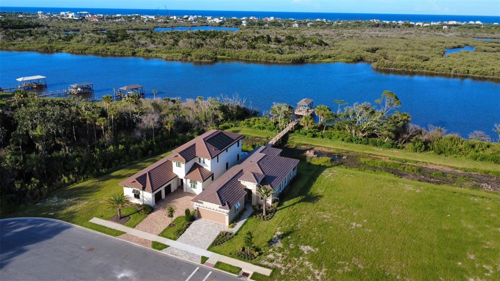 An aerial view shows a large house with a brown roof near a waterfront dock — 4 CORONADO ROAD, FLAGLER BEACH, FL