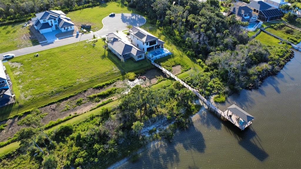 An aerial view shows a waterfront house with a pool, a long dock, and surrounding vegetation — 4 CORONADO ROAD, FLAGLER BEACH, FL