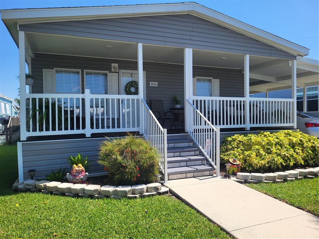 A gray manufactured home features a front porch with white railings and stairs — 3106 TERRA SIESTA BOULEVARD, ELLENTON, FL