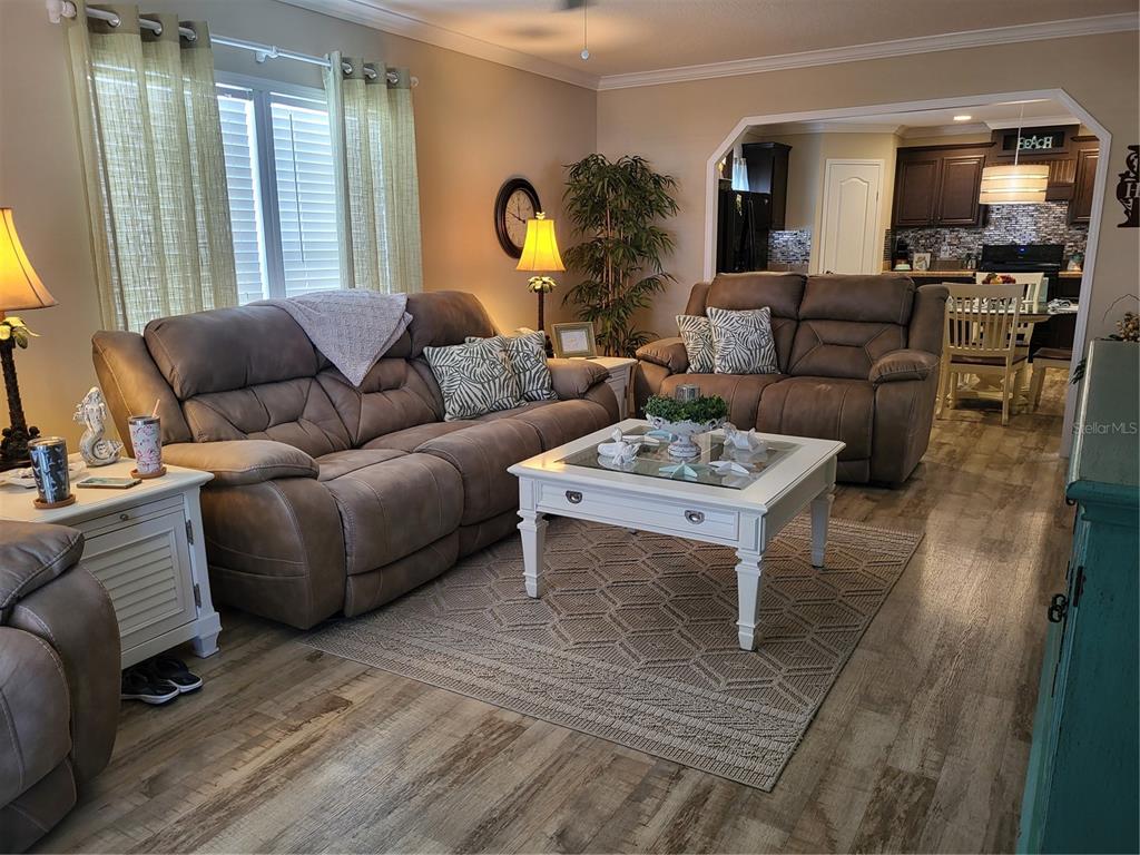A living room features brown reclining sofas, a white coffee table, and wood-look flooring — 3106 TERRA SIESTA BOULEVARD, ELLENTON, FL