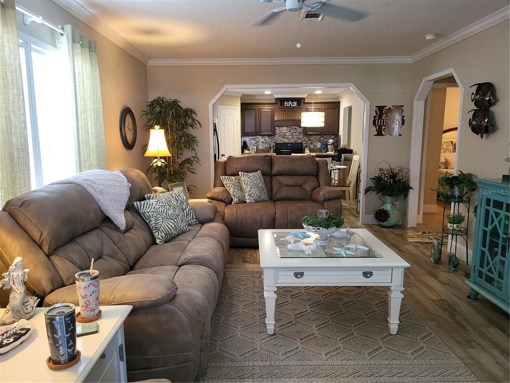 A living room with brown reclining sofas, a white coffee table, and an open kitchen — 3106 TERRA SIESTA BOULEVARD, ELLENTON, FL