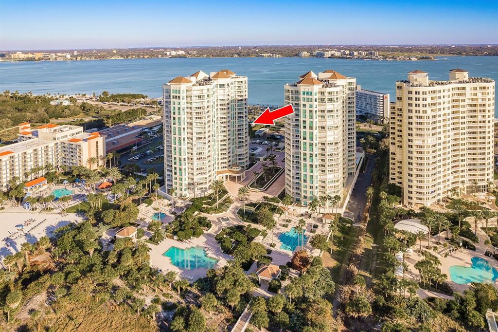 Two tall residential towers stand on a beach with a central pool and palm trees — 1170 GULF BOULEVARD SW UNIT 1105, CLEARWATER, FL