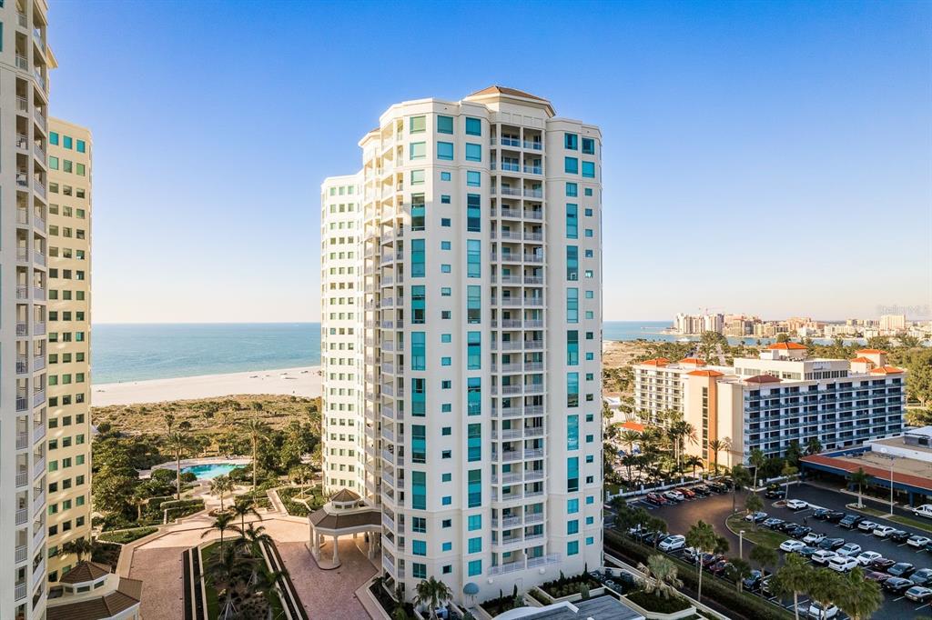 An aerial view shows three high-rise residential towers surrounded by landscaped grounds and swimming pools — 1170 GULF BOULEVARD SW UNIT 1105, CLEARWATER, FL