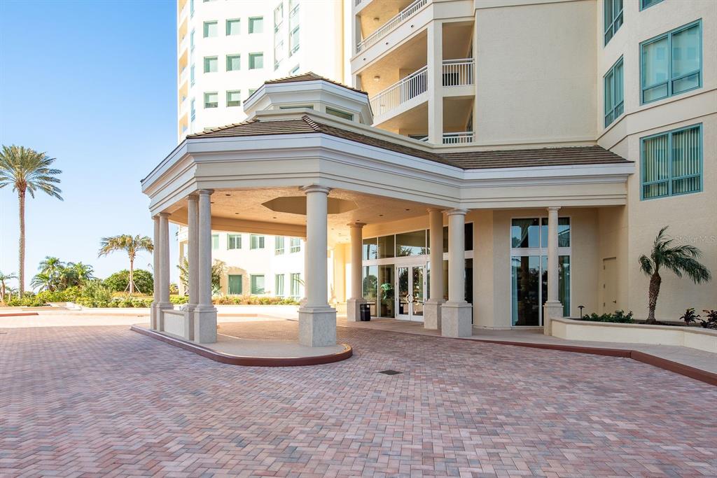 The exterior of a multi-story building features a covered porte-cochère with columns and brick paving — 1170 GULF BOULEVARD SW UNIT 1105, CLEARWATER, FL