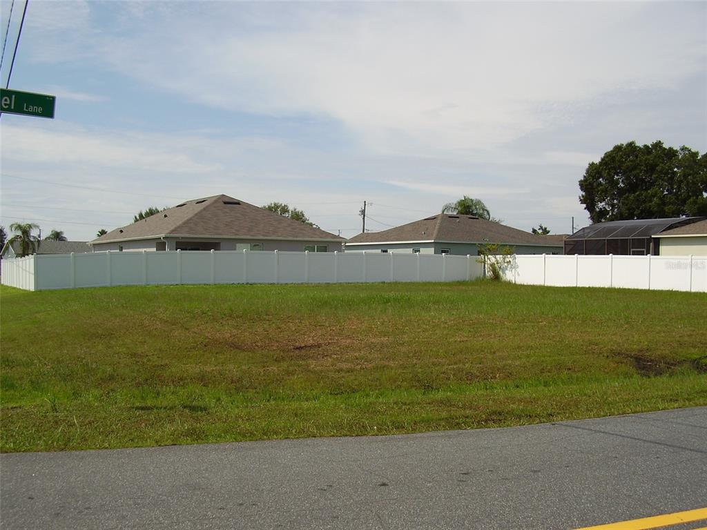 A vacant grassy lot is enclosed by a white vinyl fence in a residential neighborhood — 800 CARROUSEL LANE, KISSIMMEE, FL