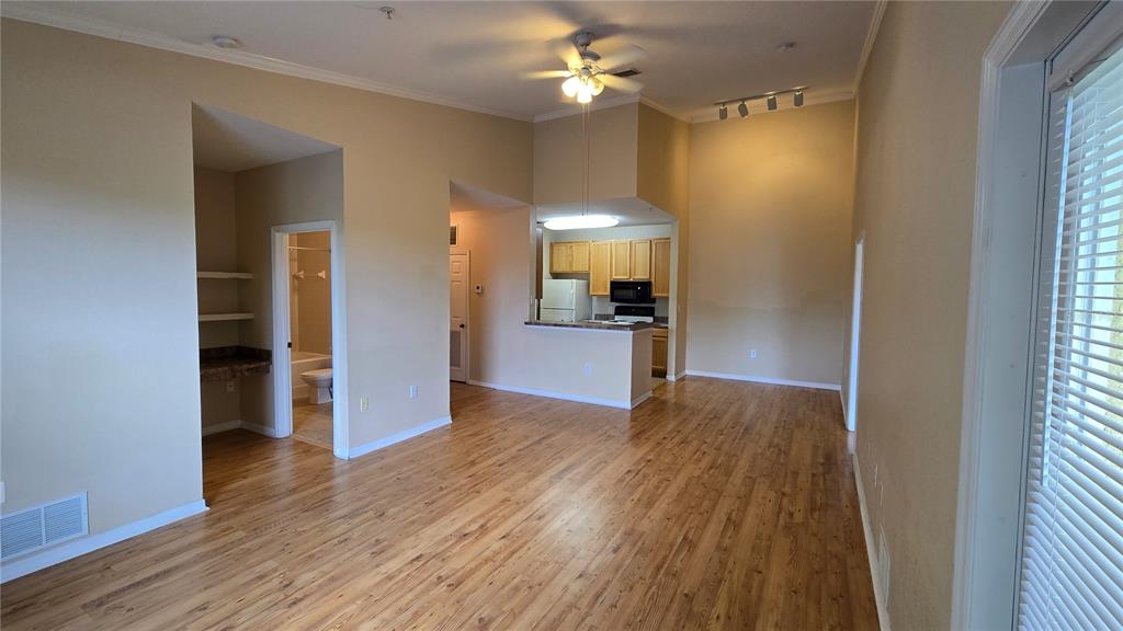 An open-concept living area with wood-look flooring, a kitchen with light wood cabinets, and a bathroom — 10211 COURTNEY PALMS BOULEVARD UNIT 304, TAMPA, FL