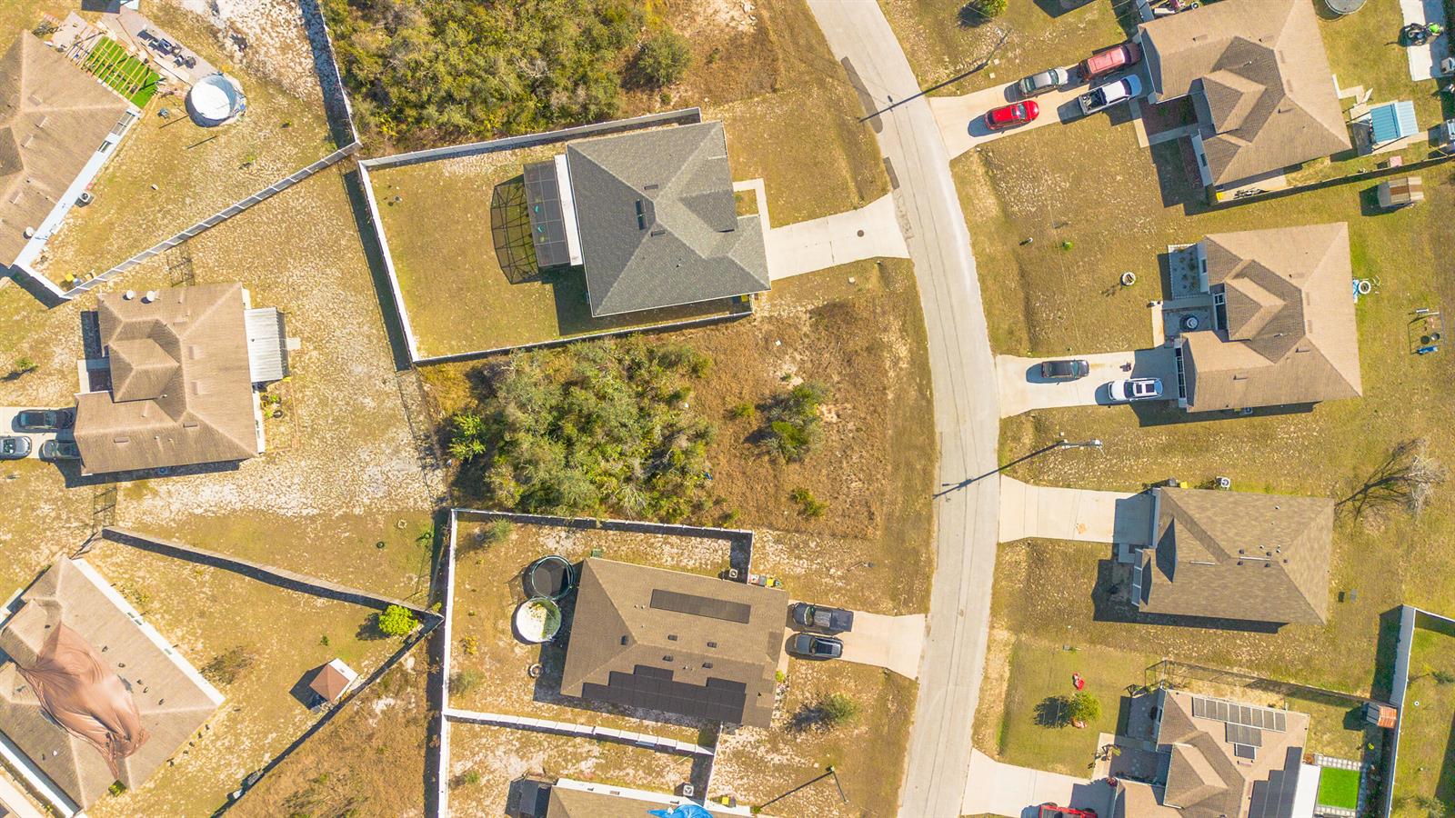 This aerial view shows several suburban houses with driveways and fenced yards — 19 Orchid Court, FL 34759, FL