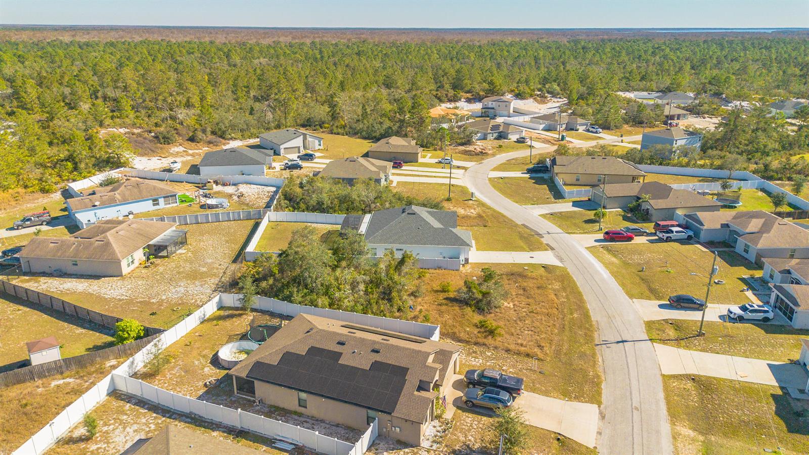 An aerial view shows a suburban neighborhood with houses, driveways, and surrounding wooded areas — 19 Orchid Court, FL 34759, FL