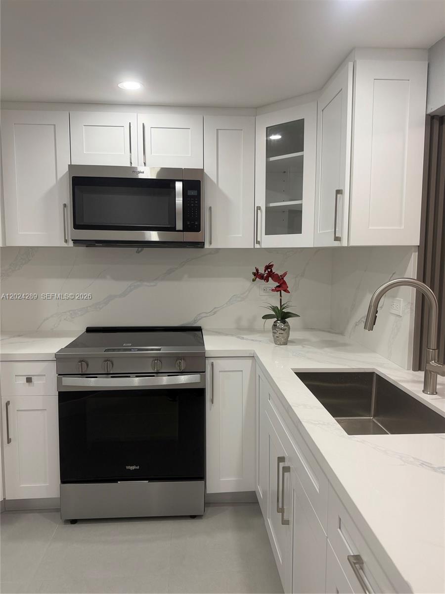 A modern kitchen features white cabinets, stainless steel appliances, and white marble-patterned countertops — 10233 NW 9th St Cir # 1, Miami FL 33172, MIAMI, FL