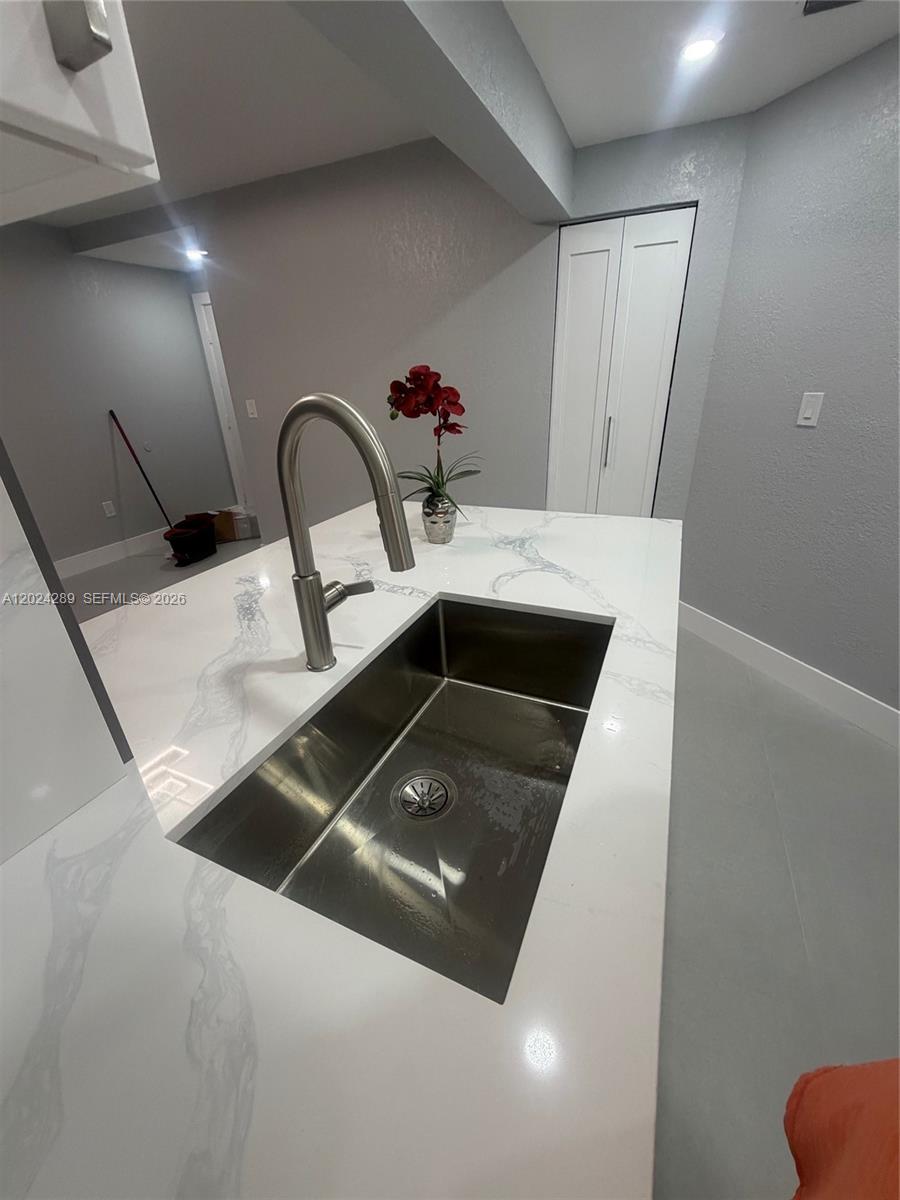 A kitchen island features a stainless steel undermount sink, a gooseneck faucet, and marble-patterned countertops — 10233 NW 9th St Cir # 1, Miami FL 33172, MIAMI, FL