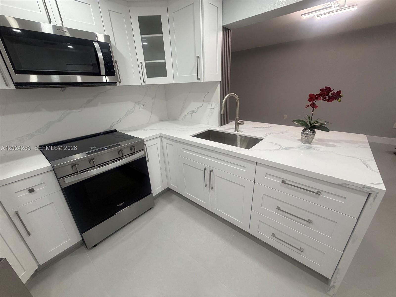 A modern kitchen features white cabinets, stainless steel appliances, and white marble-patterned countertops — 10233 NW 9th St Cir # 1, Miami FL 33172, MIAMI, FL