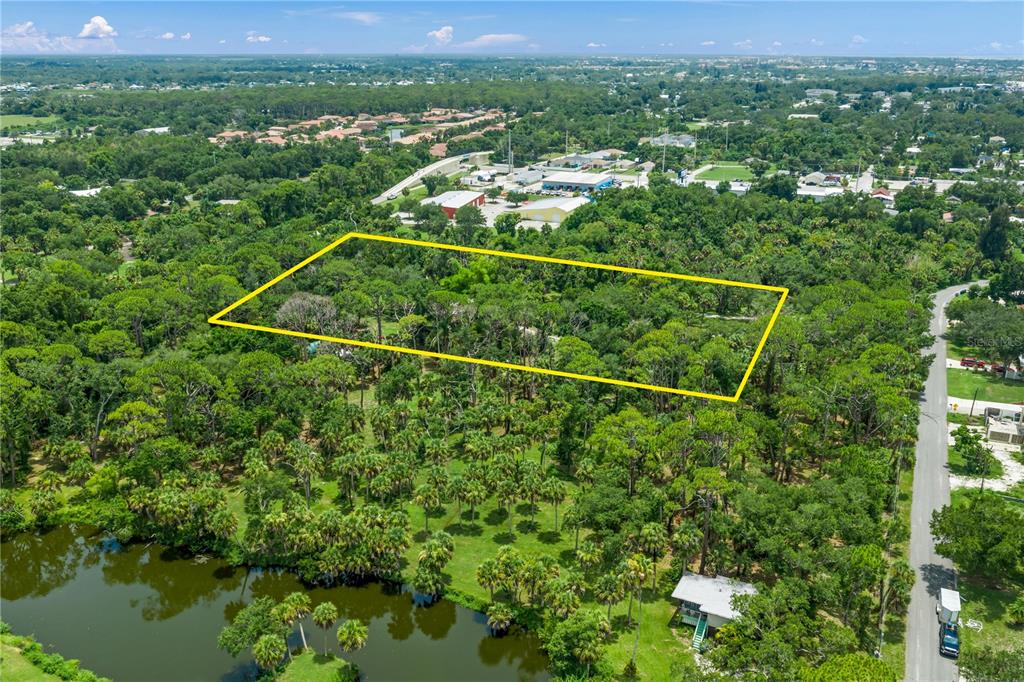 An aerial view shows a rectangular plot of land outlined in yellow near a pond — 1210 TWIN LAKES AVENUE, NOKOMIS, FL