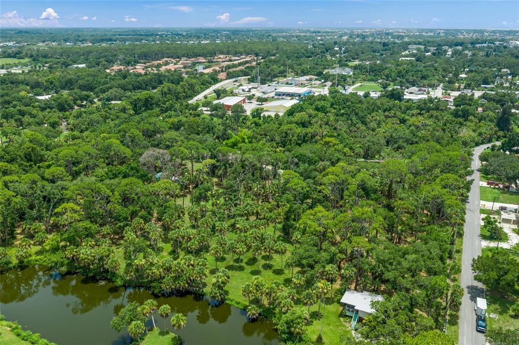 An aerial view shows a wooded property with a pond and a small house nearby — 1210 TWIN LAKES AVENUE, NOKOMIS, FL