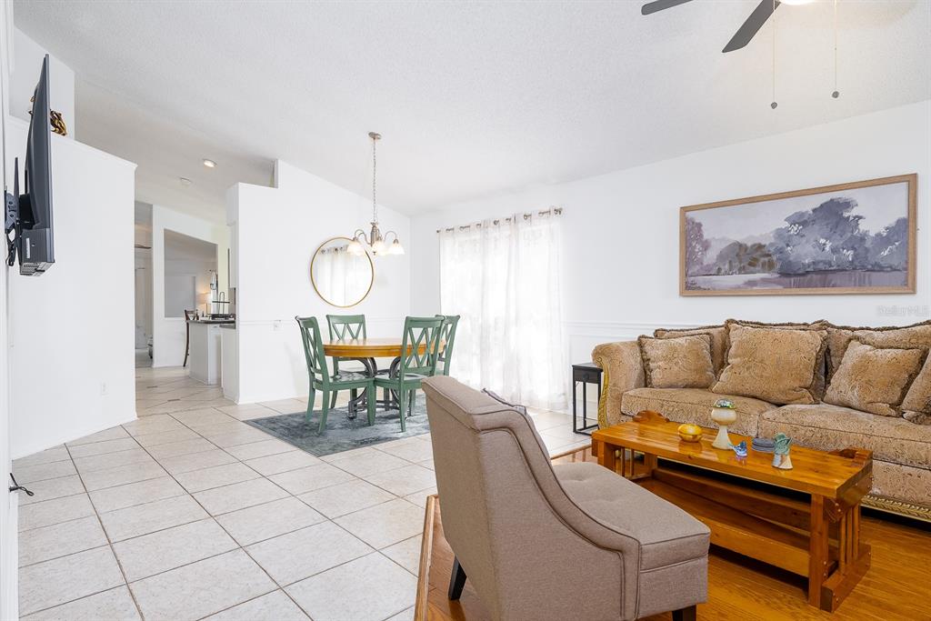 A living room and dining area with tile and wood flooring and white walls — 254 OAK PARK PLACE, CASSELBERRY, FL