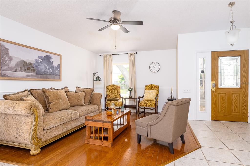 A living room features a sofa, armchairs, a wooden coffee table, and hardwood flooring — 254 OAK PARK PLACE, CASSELBERRY, FL