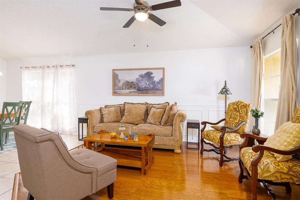 A living room features hardwood floors, a ceiling fan, a sofa, and two patterned armchairs — 254 OAK PARK PLACE, CASSELBERRY, FL