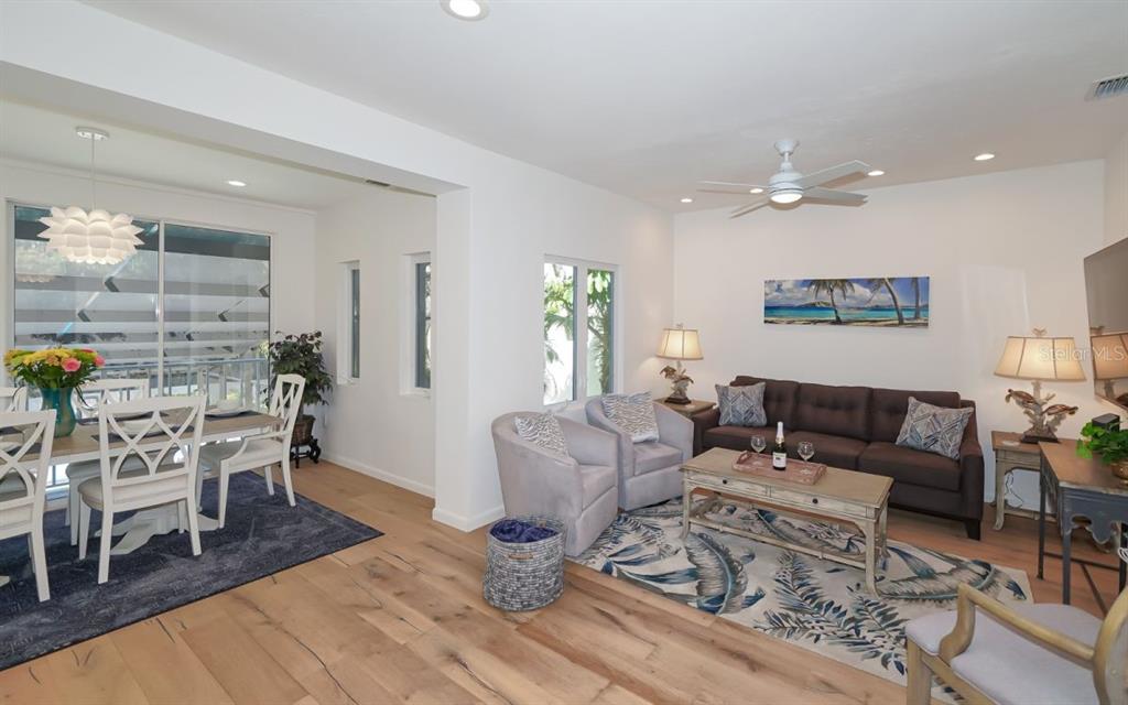 An open-concept living and dining area features light wood flooring, white walls, and coastal decor — 228 VAN BUREN DRIVE, SARASOTA, FL