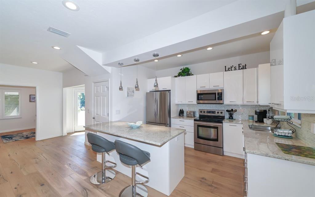 A modern kitchen features white cabinets, stainless steel appliances, granite countertops, and a central island — 228 VAN BUREN DRIVE, SARASOTA, FL