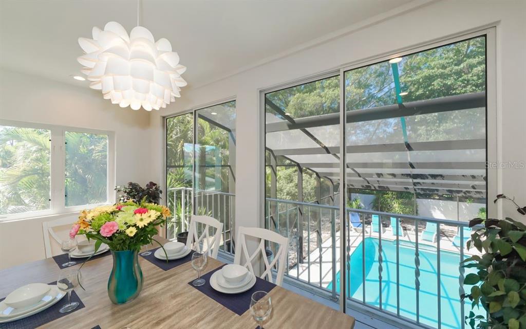 A dining room with a floral chandelier overlooks a screened-in pool area through sliding doors — 228 VAN BUREN DRIVE, SARASOTA, FL