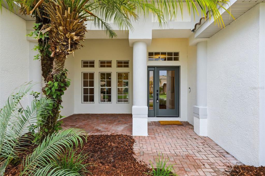 A covered entryway features a brick-paved porch, white columns, and a gray front door — 10534 BERMUDA ISLE DRIVE, TAMPA, FL