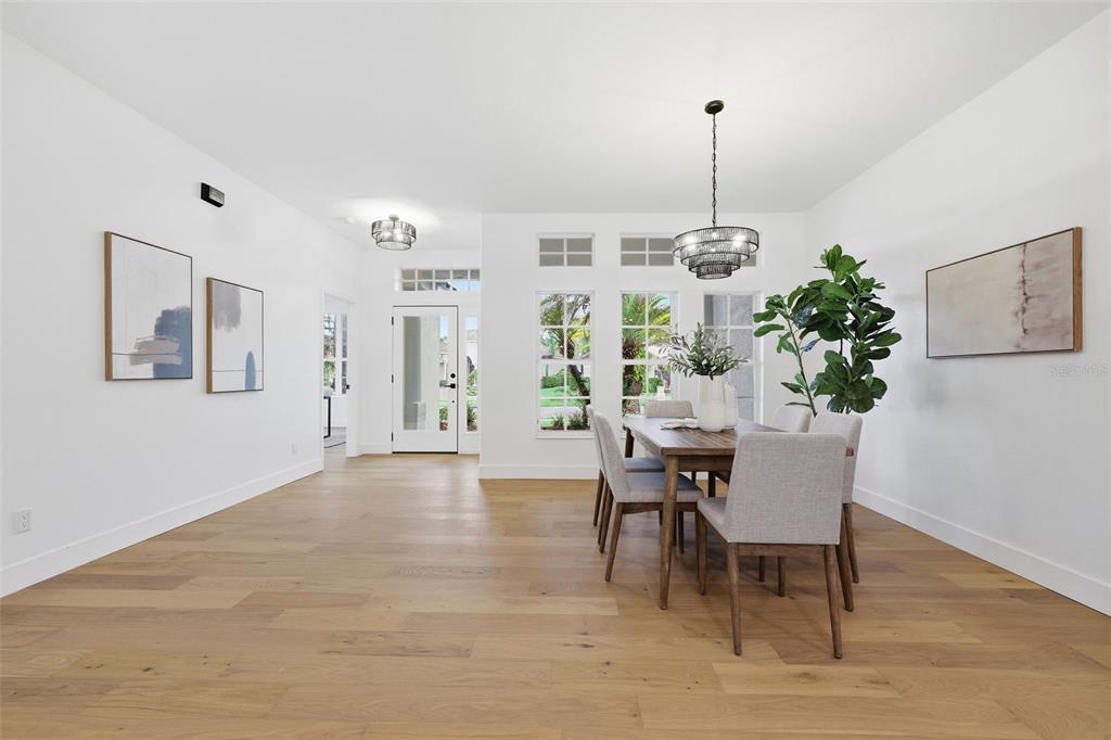 A dining room with light wood floors, a wooden table, and a modern chandelier — 10534 BERMUDA ISLE DRIVE, TAMPA, FL