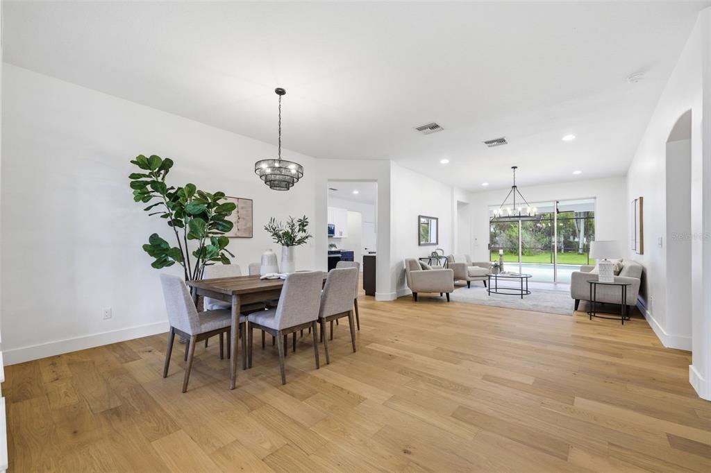 An open-concept dining and living area features light wood flooring, white walls, and sliding doors — 10534 BERMUDA ISLE DRIVE, TAMPA, FL