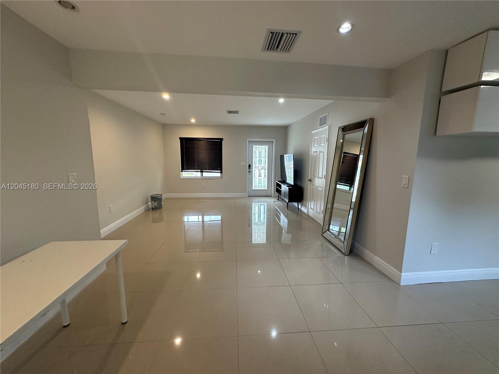A bright, open-concept living area features large light-colored floor tiles and a full-length mirror — 2155 Biarritz Dr, Miami Beach FL 33141, MIAMI BEACH, FL