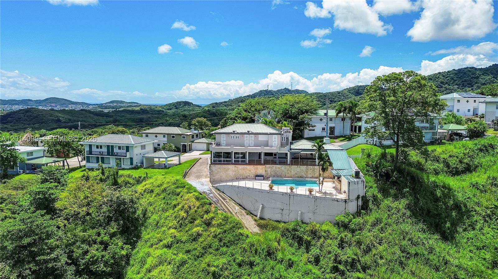 A two-story house with a white garage, palm trees, and a central front entrance — 95 N Melao, PR 00773, PR