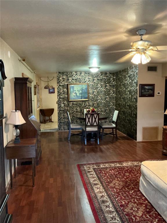 A dining area with patterned wallpaper and a ceiling fan sits adjacent to a living space — 4300 58TH STREET N UNIT 1801, KENNETH CITY, FL