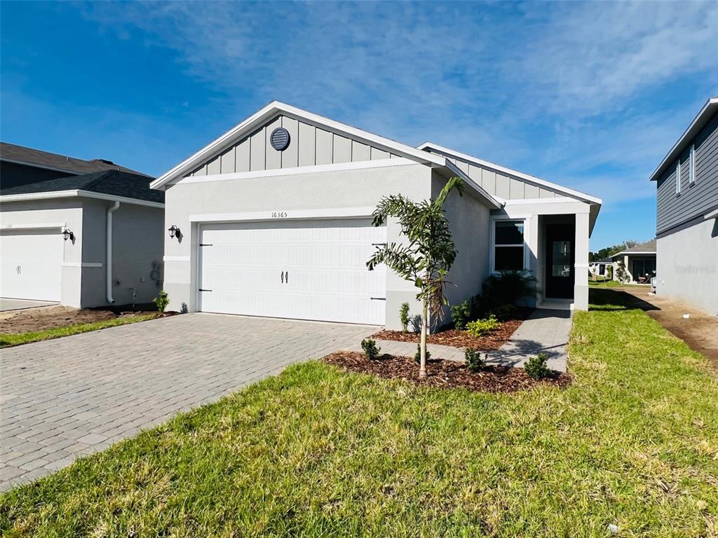 A single-story house with a white garage door, gray siding, and a paved driveway — 16365 WINDING PRESERVE CIRCLE, CLERMONT, FL
