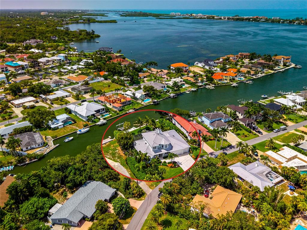 An aerial view shows a large house with a gray roof situated on a canal — 7631 COVE TERRACE, SARASOTA, FL