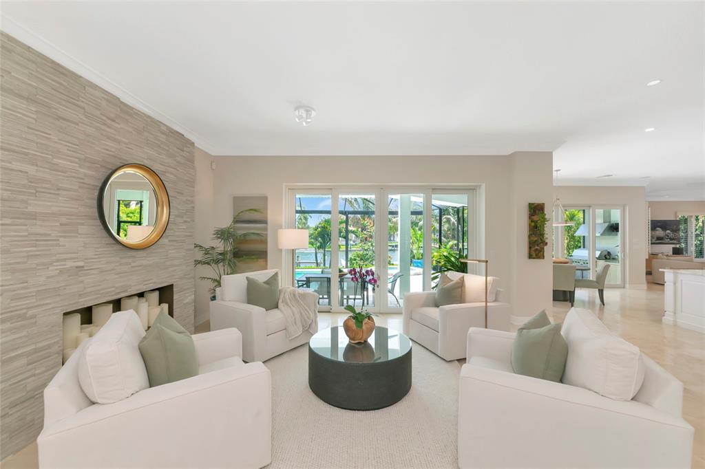 A living room features four white armchairs, a round coffee table, and a stone fireplace — 7631 COVE TERRACE, SARASOTA, FL