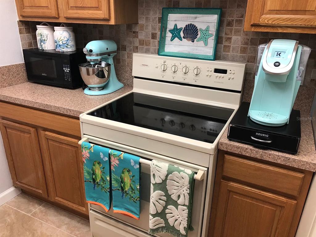 A kitchen features light wood cabinets, a white stove, and light blue small appliances — 2621 COVE CAY DRIVE UNIT 105, CLEARWATER, FL