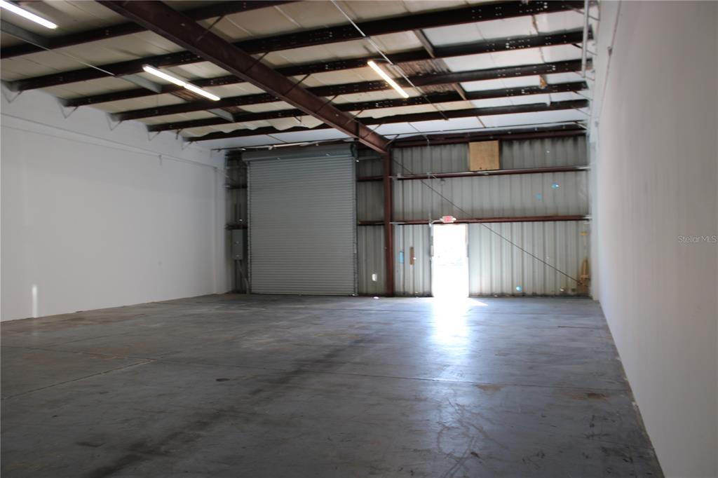 An empty warehouse space with a concrete floor, metal walls, and a roll-up door — 1400 L AND R INDUSTRIAL BOULEVARD Bldg. A, TARPON SPRINGS, FL