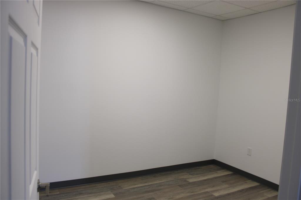An empty office room features white walls, dark baseboards, and wood-look vinyl plank flooring — 1400 L AND R INDUSTRIAL BOULEVARD Bldg. A, TARPON SPRINGS, FL
