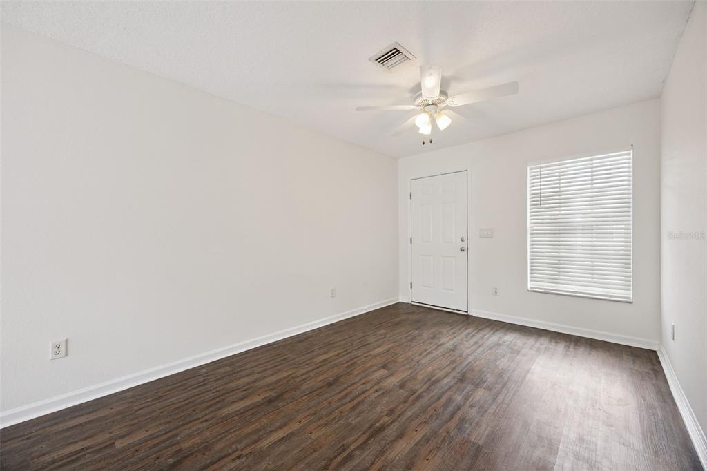 An empty room with white walls, dark wood-look flooring, a ceiling fan, and a window — 1105 N ROCKINGHAM AVENUE, TAVARES, FL