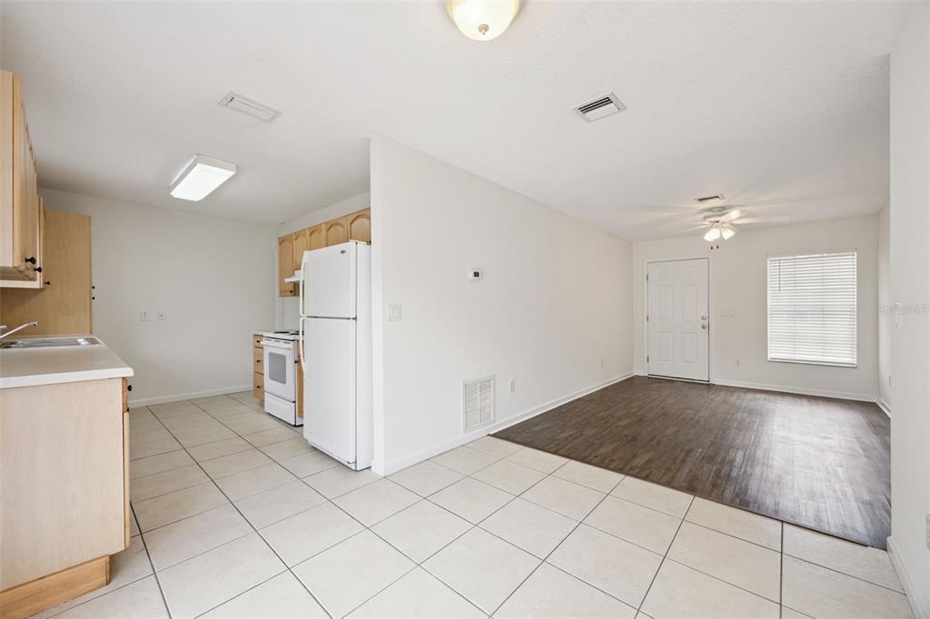 A kitchen with tile flooring and light wood cabinets opens into a living area — 1105 N ROCKINGHAM AVENUE, TAVARES, FL